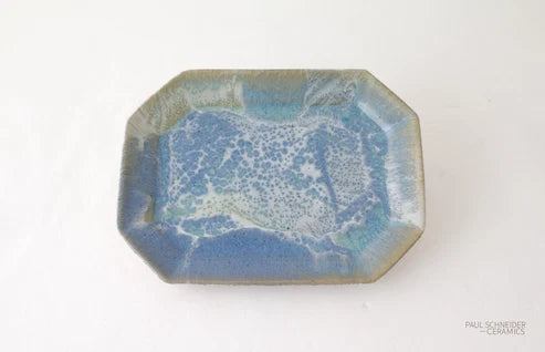 An octagonal ceramic dish with a textured, marbled glaze in shades of blue, teal, and white, set against a plain white background.