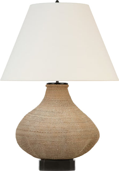 Table lamp with woven base and white shade on a white background