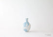 Small ceramic vase with blue and white abstract pattern on a light gray background