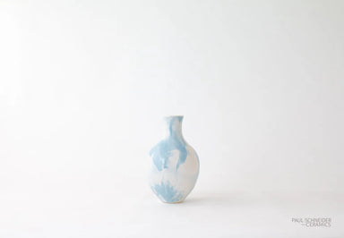 Small ceramic vase with blue and white abstract pattern on a light gray background