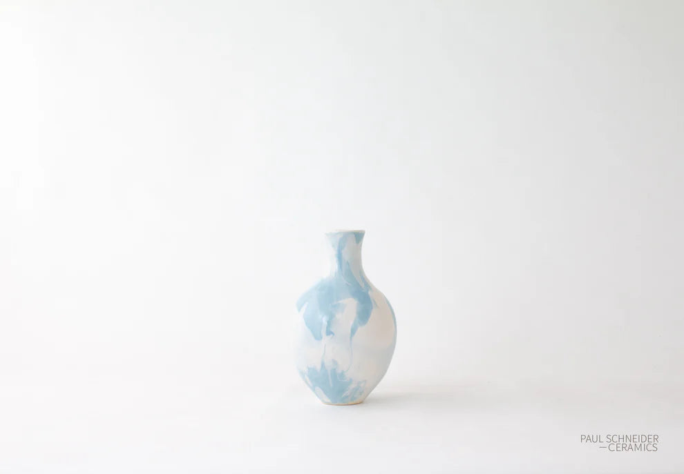 Small ceramic vase with blue and white abstract pattern on a light gray background