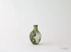 Green ceramic vase with white patterns on a white background