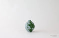 Small ceramic vase with green design on a white background