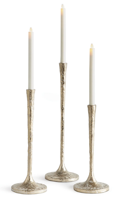 Three textured metallic candlesticks with flared bases, each holding a white taper candle, shown on a clean white background.