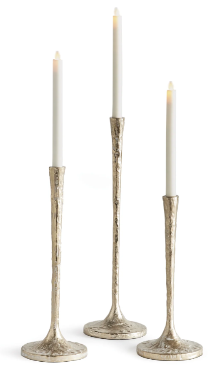 Three textured metallic candlesticks with flared bases, each holding a white taper candle, shown on a clean white background.