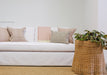 white sofa with pink pillows and wicker side table