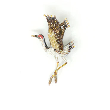 Decorative brooch of a bird with gold and silver accents on a white background