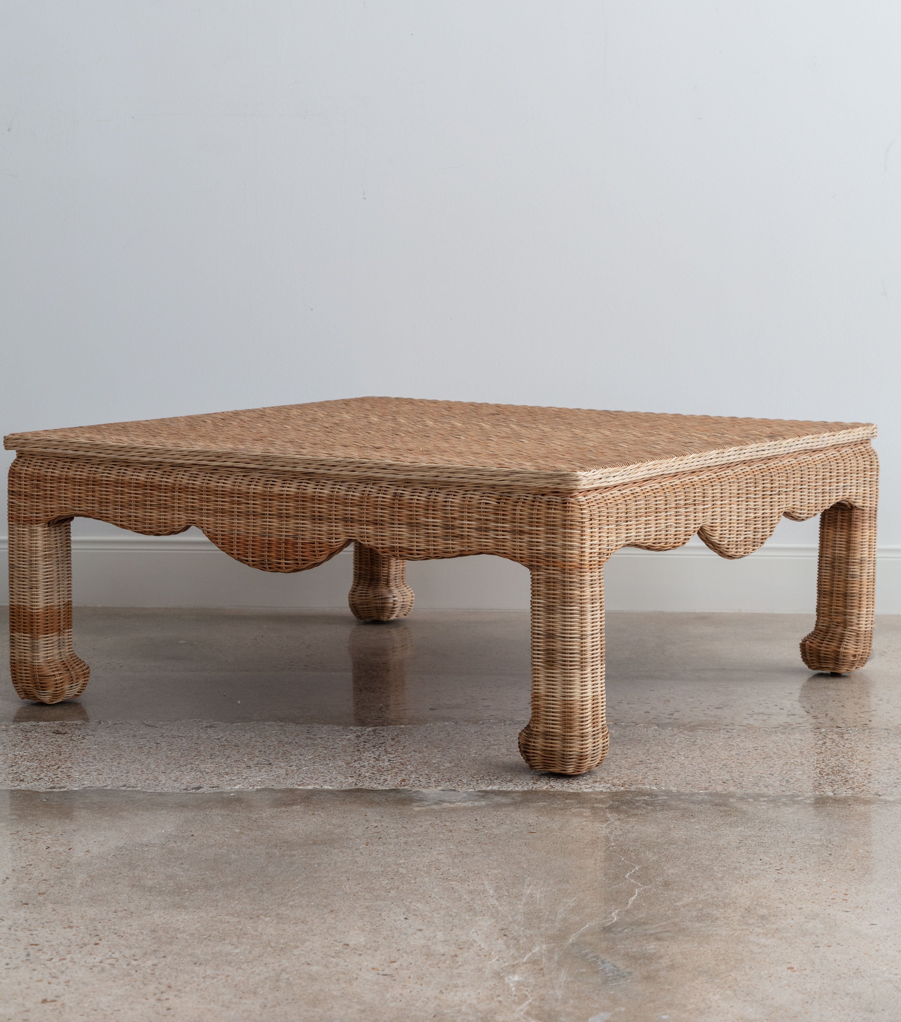 angled view of a wicker coffee table with curved feet and apron