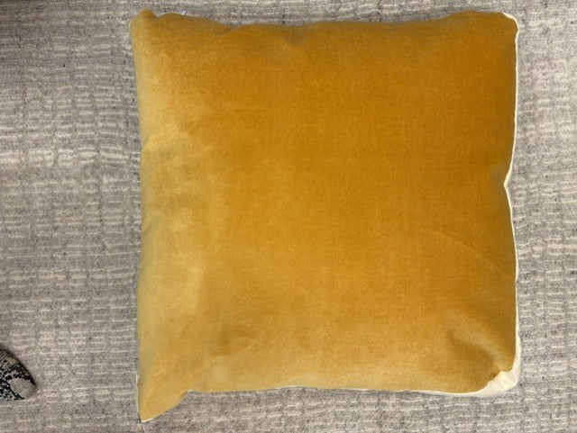 A square butterscotch yellow velvet throw pillow with a white piped edge, resting on a textured gray fabric background.