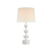A modern white table lamp with a sculptural, flower-like base and a tapered drum shade, shown illuminated against a plain white background.