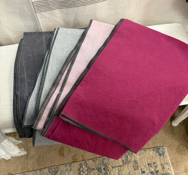 Stack of folded cloths in various colors on a surface.