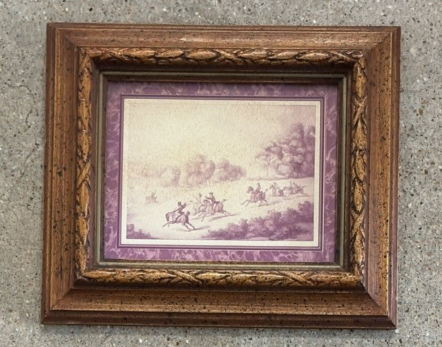 A framed art print featuring a vintage illustration of horse racing, set in an ornate brown wooden frame with a purple mat border, displayed against a textured gray concrete wall.
