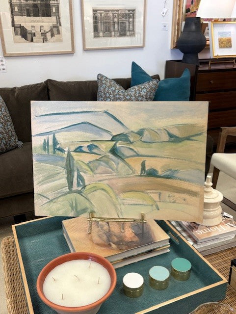 Landscape painting on a coffee table with candles and books in a living room setting