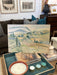 Landscape painting on a coffee table with candles and books in a living room setting