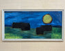Framed painting of a night scene with a full moon and silhouettes on a beige wall.