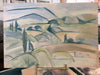 Painting of a landscape with green hills and blue sky on an easel.