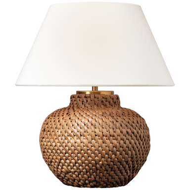 Table lamp with woven base and white shade on a white background