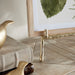 Gold bird sculpture and decorative easel holding a framed piece of art on a wooden surface with a neutral background
