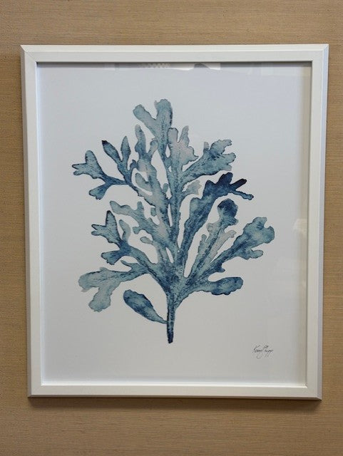 Framed artwork of a blue leaf design on a beige wall
