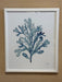 Framed artwork of a blue leaf design on a beige wall