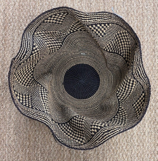 Black and beige woven hat on a beige surface