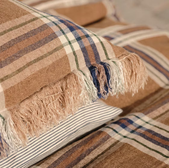 Plaid piillow with fringes on a textured surface