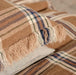 Plaid piillow with fringes on a textured surface