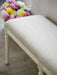 Linen upholstered bench with floral arrangement in the background