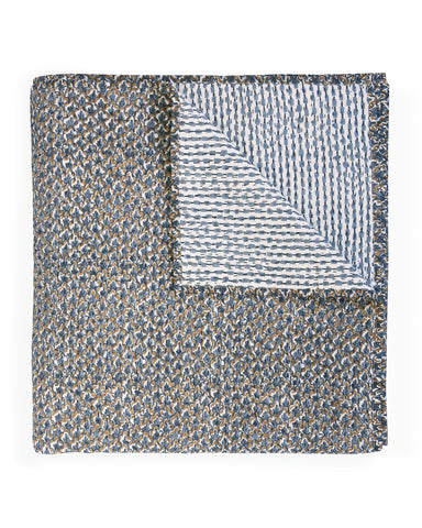 A folded quilt with a textured, speckled blue, gray, and beige pattern on one side and a contrasting block printed pattern in blue and beige on the reverse, shown on a plain white background.