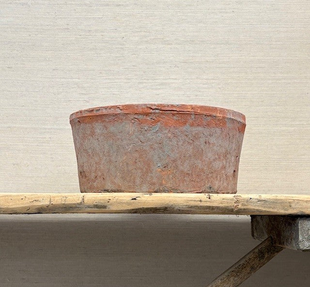 Rust-colored pot on a wooden surface with a neutral background