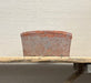 Rust-colored pot on a wooden surface with a neutral background