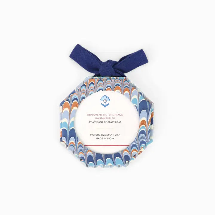 A marbled octagonal ornament picture frame with a navy blue ribbon bow at the top, featuring a central white label with blue and orange wave patterns.