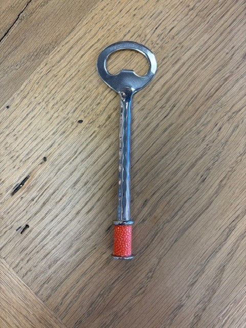 Metal bottle opener with red handle on a wooden surface