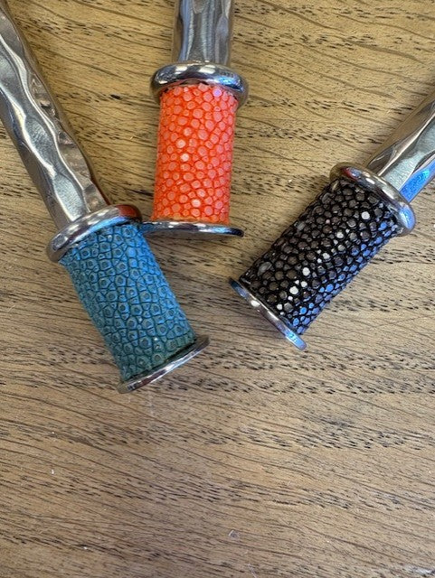 Three handles with different colored grips on a wooden surface
