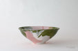 Ceramic bowl with green and pink glazed design on a white background