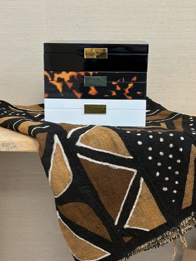 Three stacked decorative boxes with tortoiseshell and white design on a textured surface.