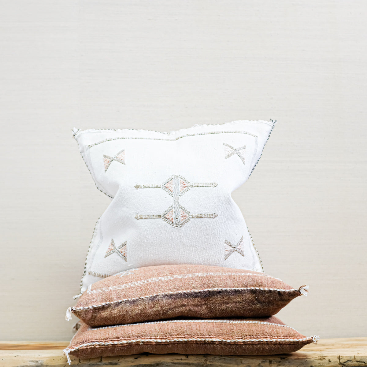 trio of moroccan square pillows with nubby woven texture and embroidered pattern