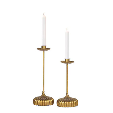 Two gold candle holders with white candles on a white background