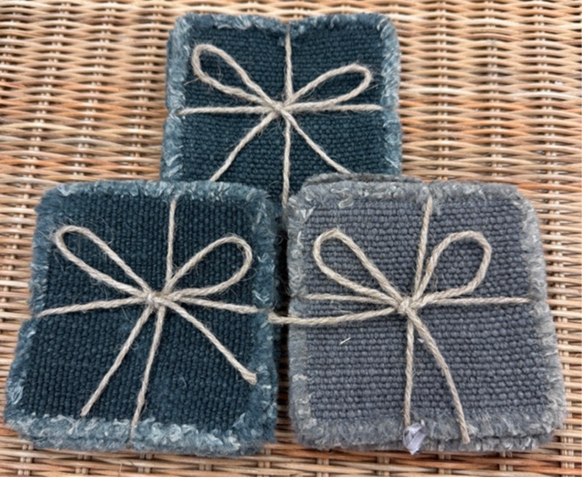 Three linen coaster sets with string bows on a wicker surface
