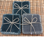 Three linen coaster sets with string bows on a wicker surface