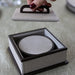 Round textured object in a box with a hand lifting the lid.