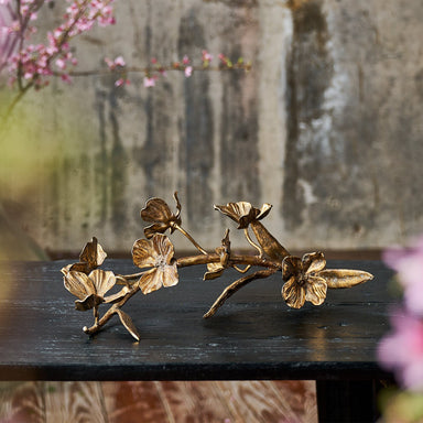 Bronze floral sculpture on a dark surface with a blurred natural background