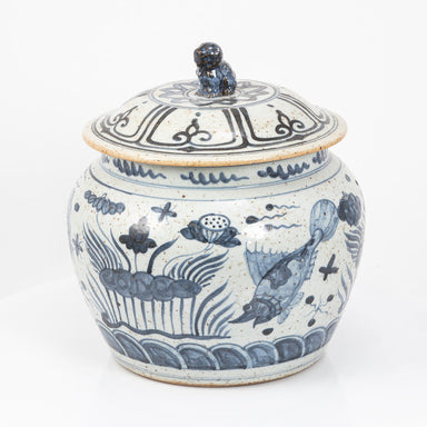 Blue and white ceramic jar with fish design on a white background