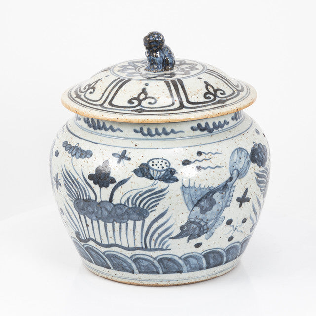 Blue and white ceramic jar with fish design on a white background