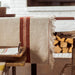 Beige tablecloth with brown stripes on a wooden table in a rustic setting.