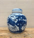 Blue and white ceramic jar with nature-themed design on a wooden surface.