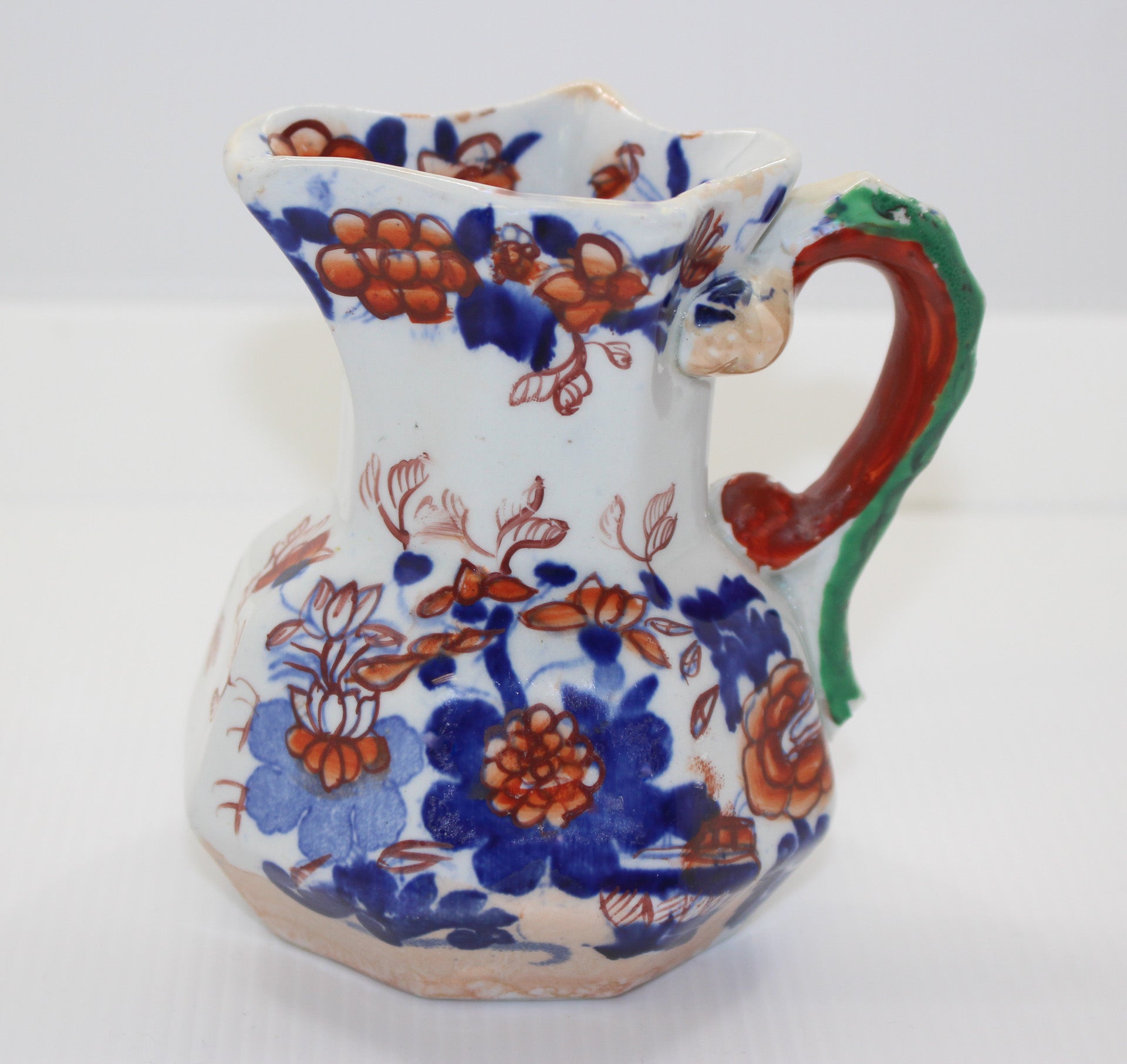 Decorative ceramic pitcher with floral patterns on a white background