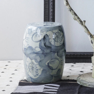 Decorative blue and white ceramic stool on a patterned rug with a neutral background
