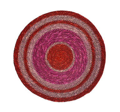 Round woven mat with concentric circular pattern in red and pink on a white background