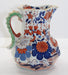 Decorative ceramic pitcher with floral patterns on a white background
